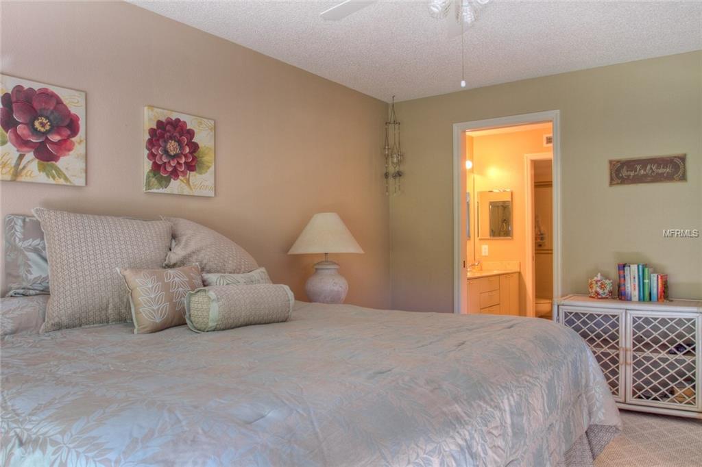 A bedroom with a large bed and floral art.