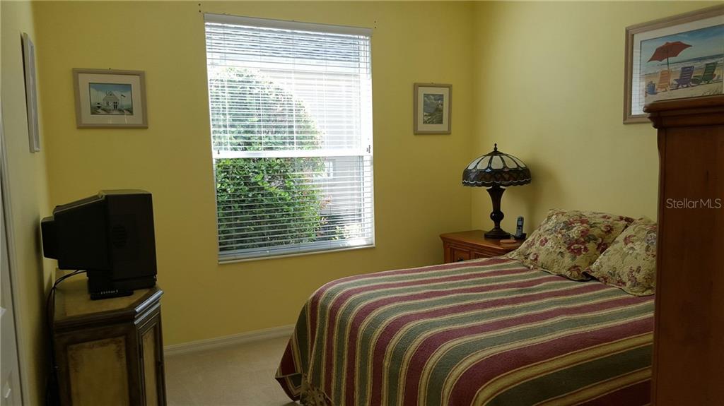 Bedroom with striped bed and window blinds.