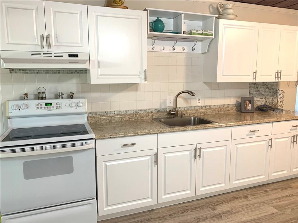 White kitchen with stainless steel sink and stove.