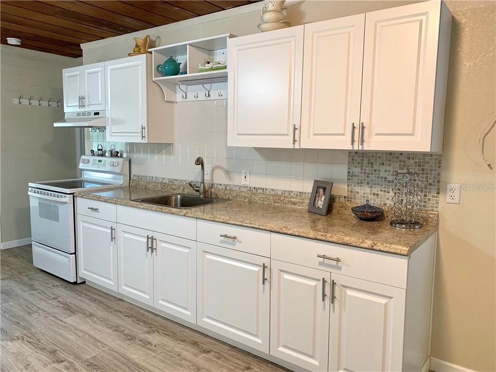 White kitchen with wood floor and cabinets.