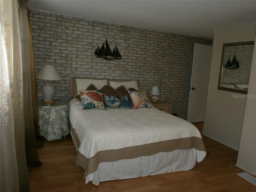 Bedroom with white bed and brick wall.