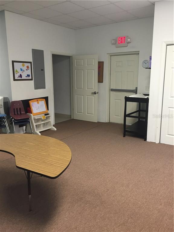 Empty classroom with table, chairs, and exit sign.