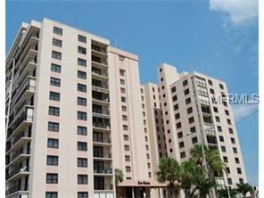 A tall, beige apartment building with palm trees.