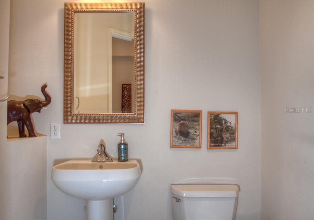 White bathroom with a mirror, sink, and toilet.