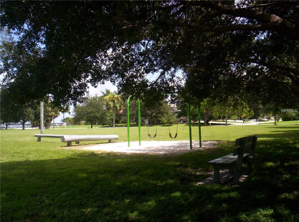 Park swings and bench under a tree.