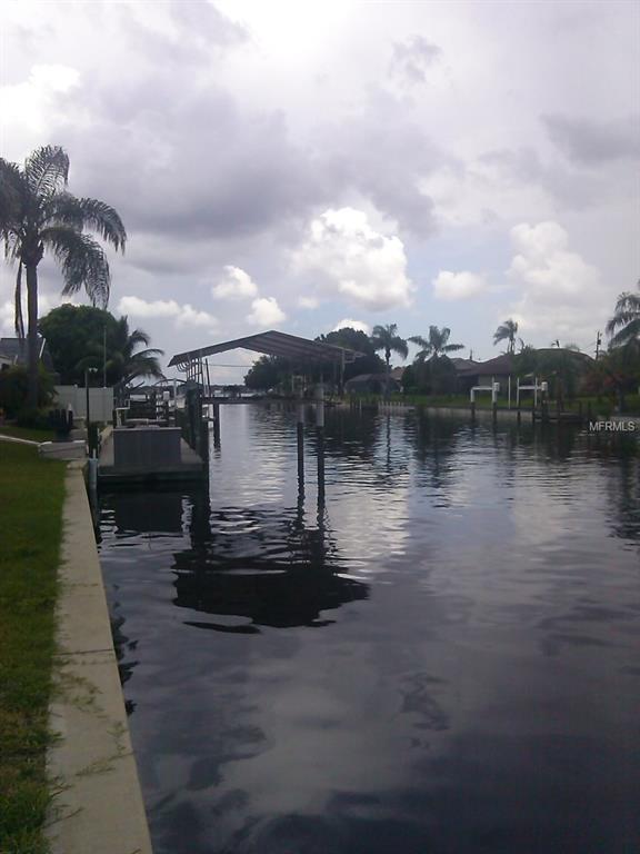 Calm canal with cloudy sky and palm trees.