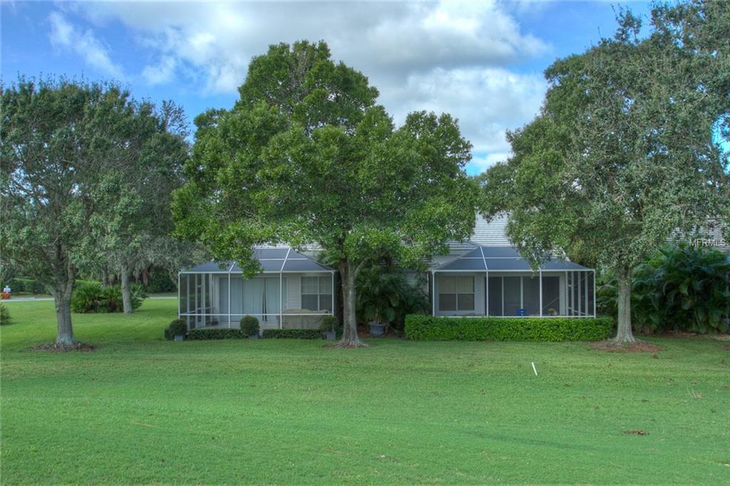 White house with screened porch and green lawn.