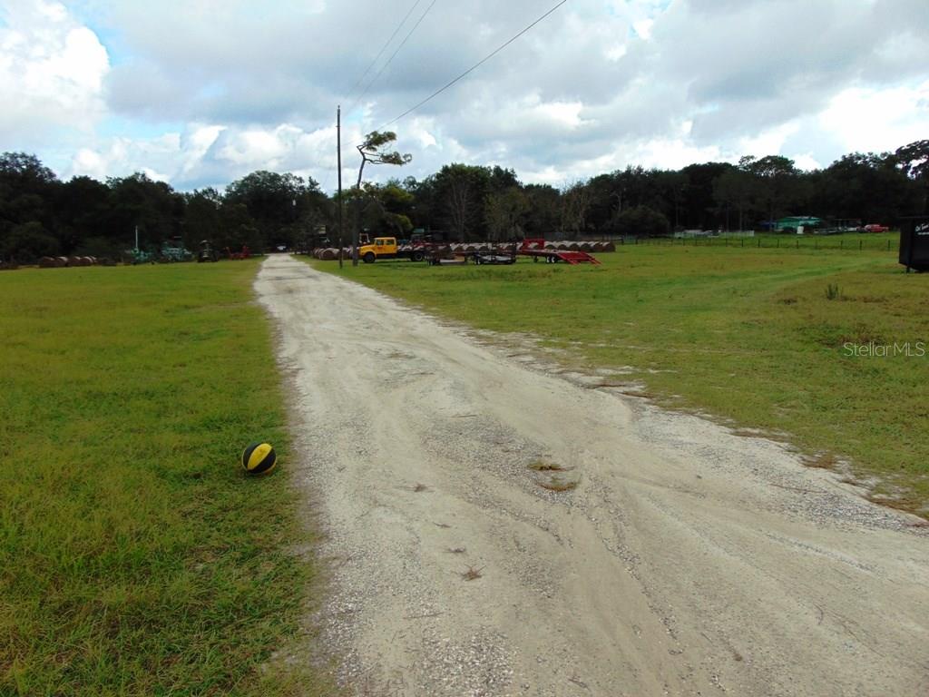 Gravel road leading through grassy field.