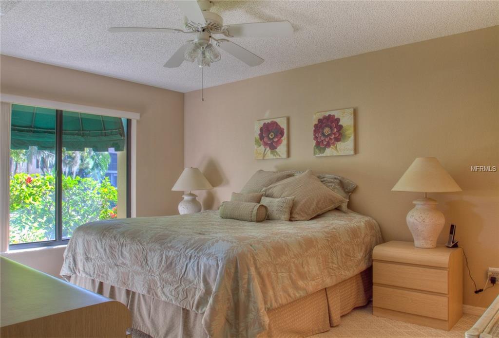 Bedroom with king bed, floral art, and window view.