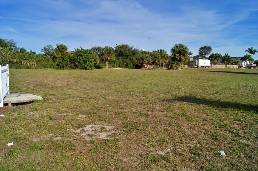 Empty grass lot with trees in background.