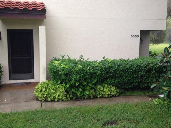 White building with green bushes and a door.