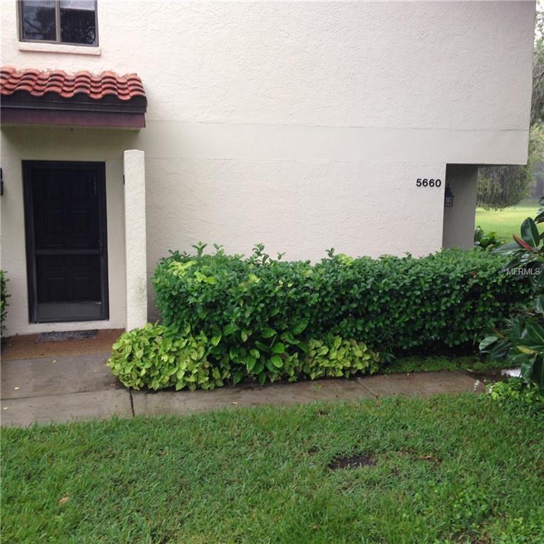 White building with green bushes and grass.