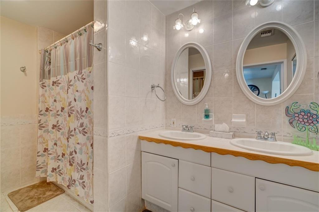 White tiled bathroom with double sinks.