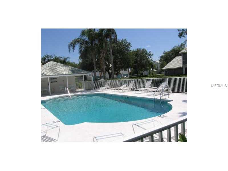 A swimming pool with lounge chairs and trees.