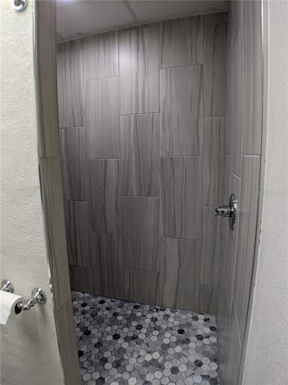 Shower stall with gray tile and hexagon floor.