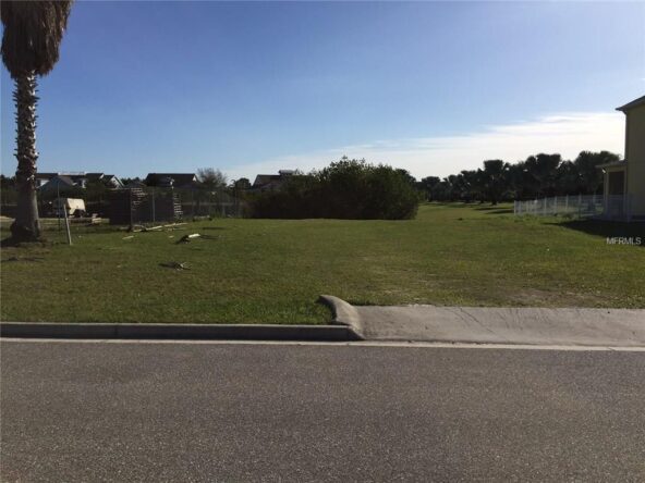 Empty grassy lot with sidewalk and curb.