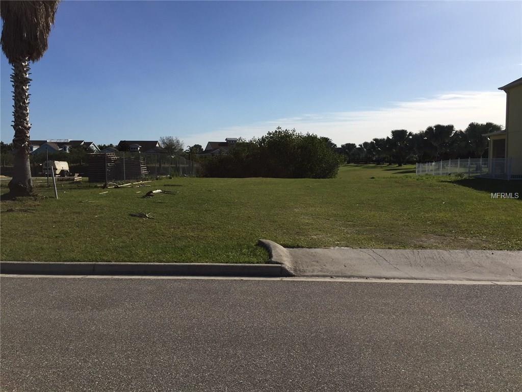 Empty grassy lot with houses in background.