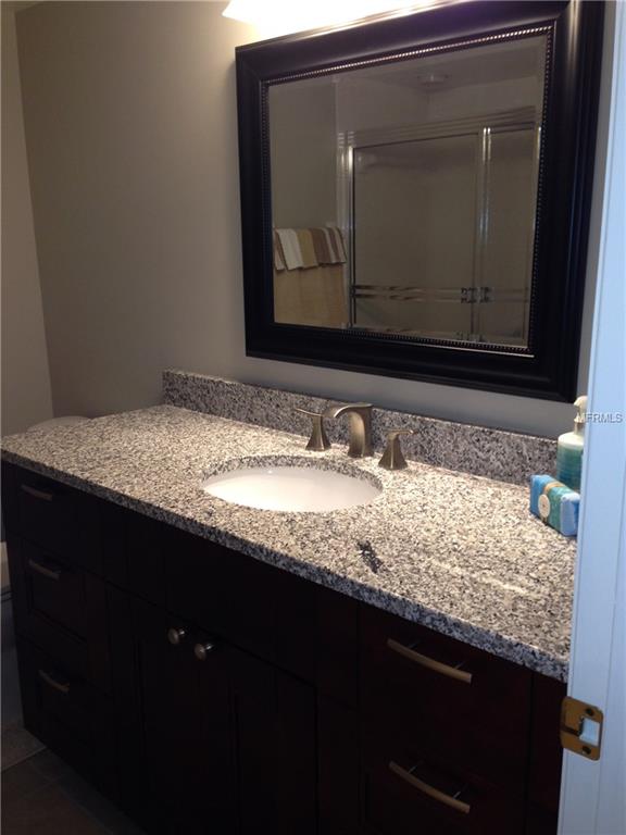 Bathroom vanity with granite countertop and sink.