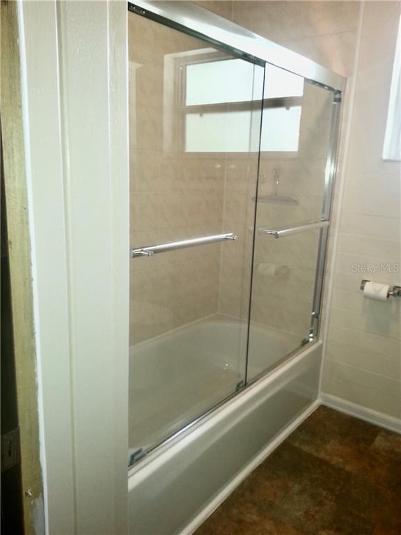 White bathtub with glass shower doors.