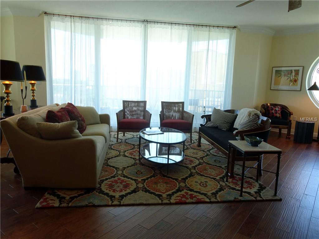 Living room with couches, rug, and large windows.