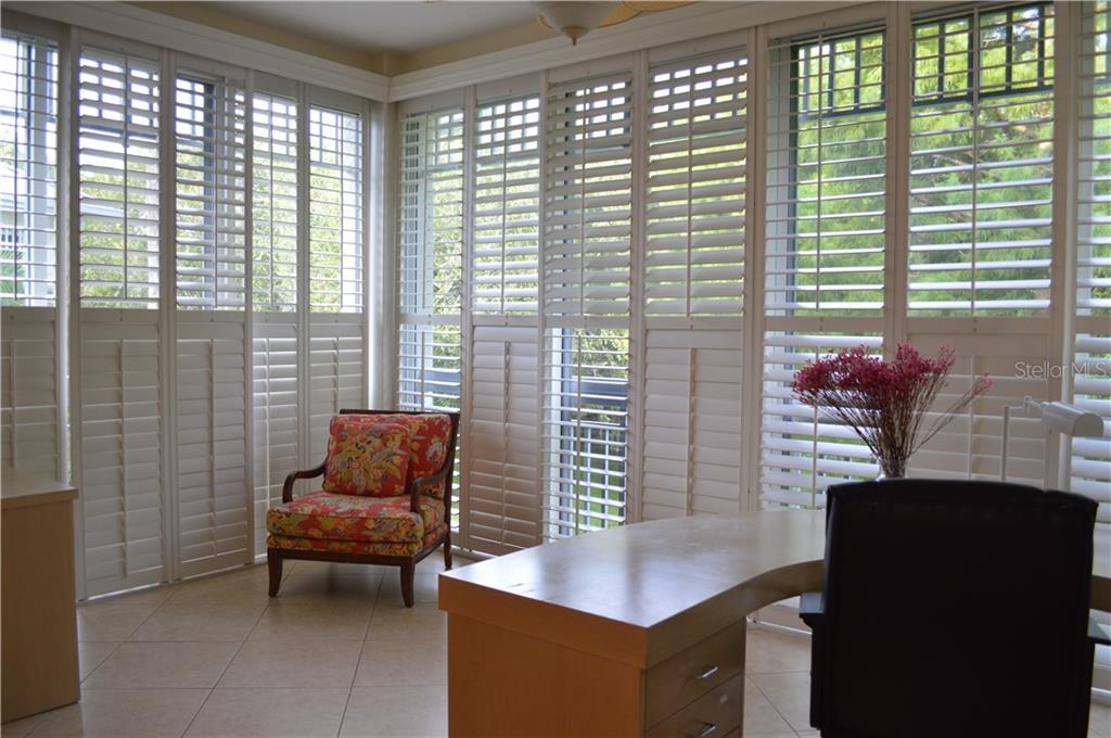 White shutters and a wooden desk with a chair.