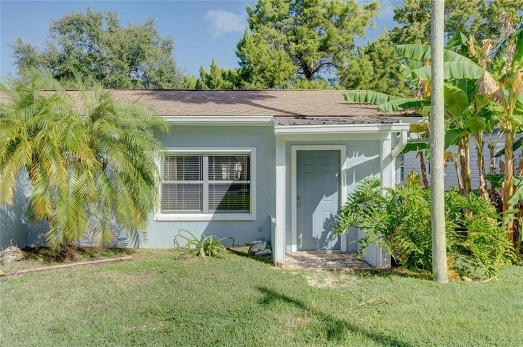 Front view of a blue house with a palm tree.