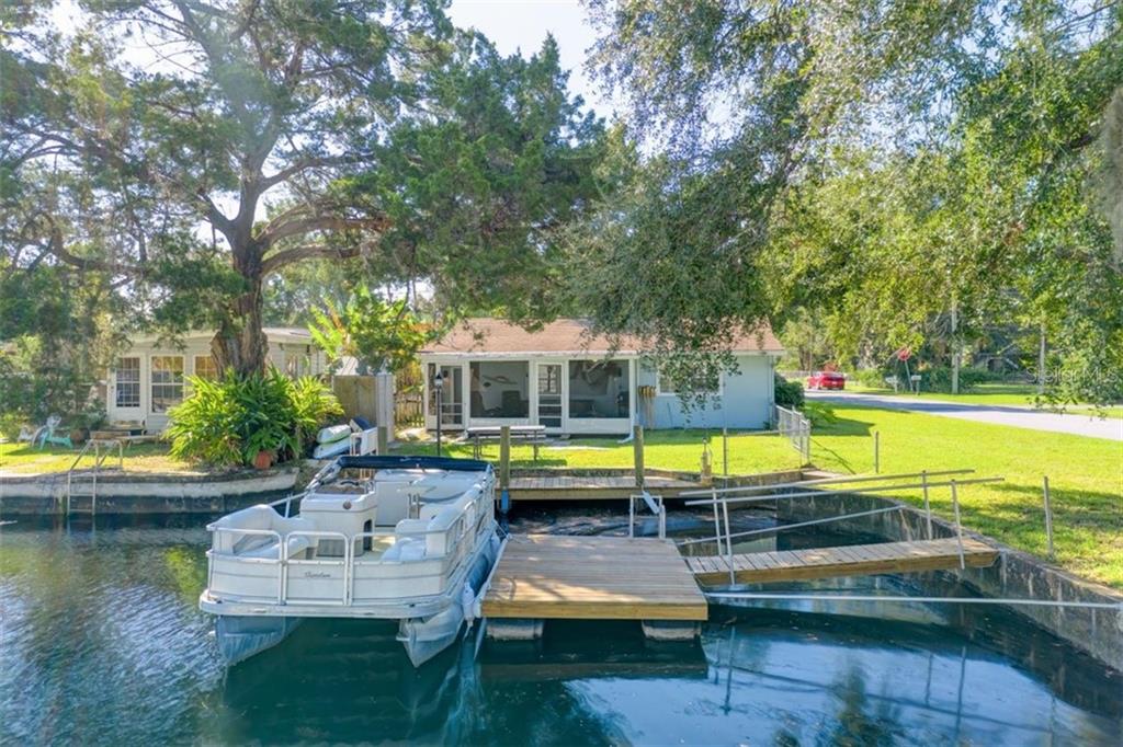 A house with a boat dock and a pontoon boat.