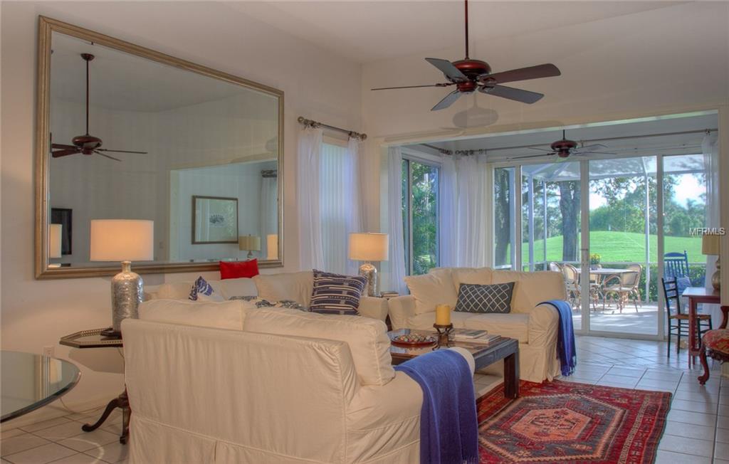 Living room with white couches and a golf course view.