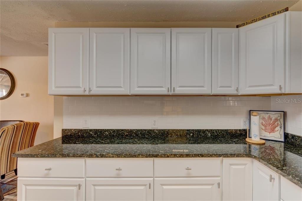 White kitchen cabinets with granite countertop.