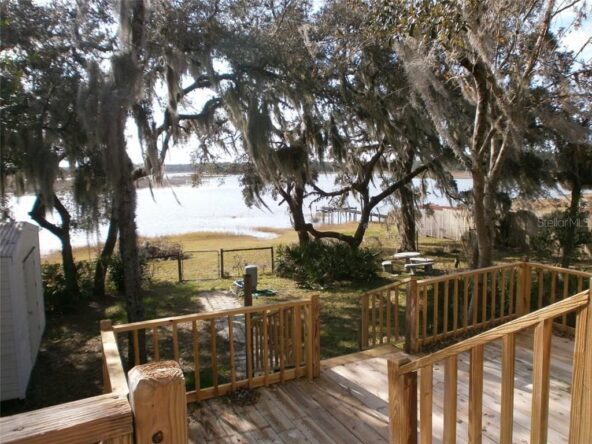 Wooden deck overlooking a lake with trees.