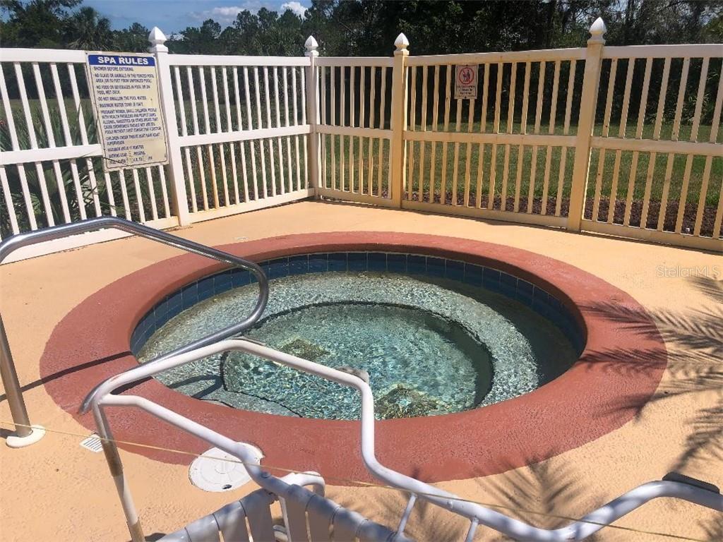 A fenced-in hot tub with blue water.