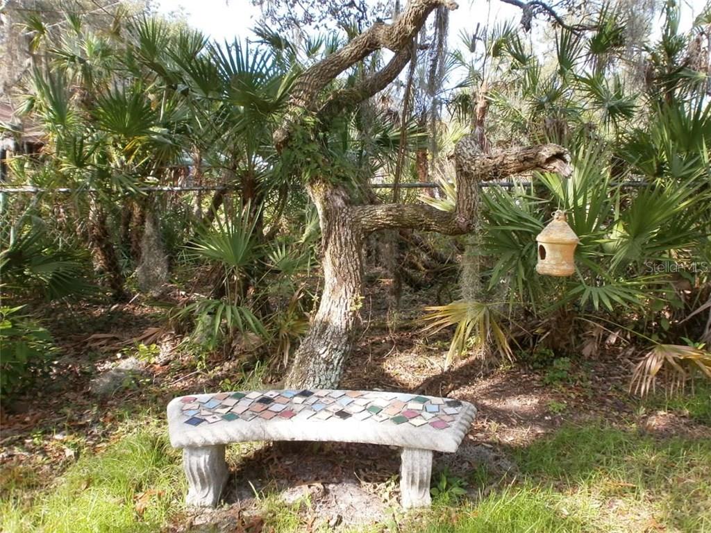 A tiled bench under a tree with a birdhouse.