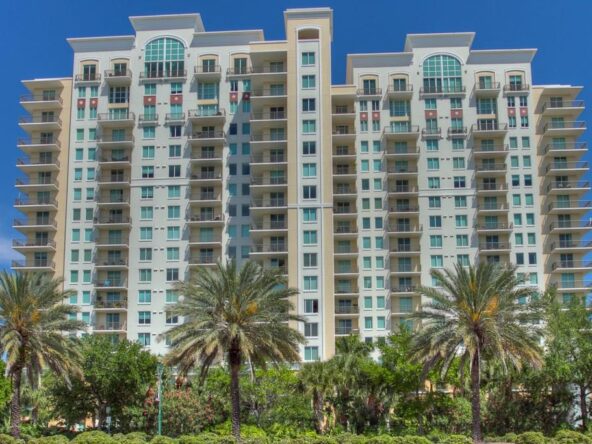 Tall beige building with palm trees.