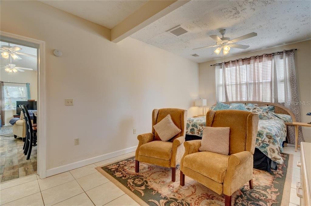 Two armchairs in a bedroom with a bed.