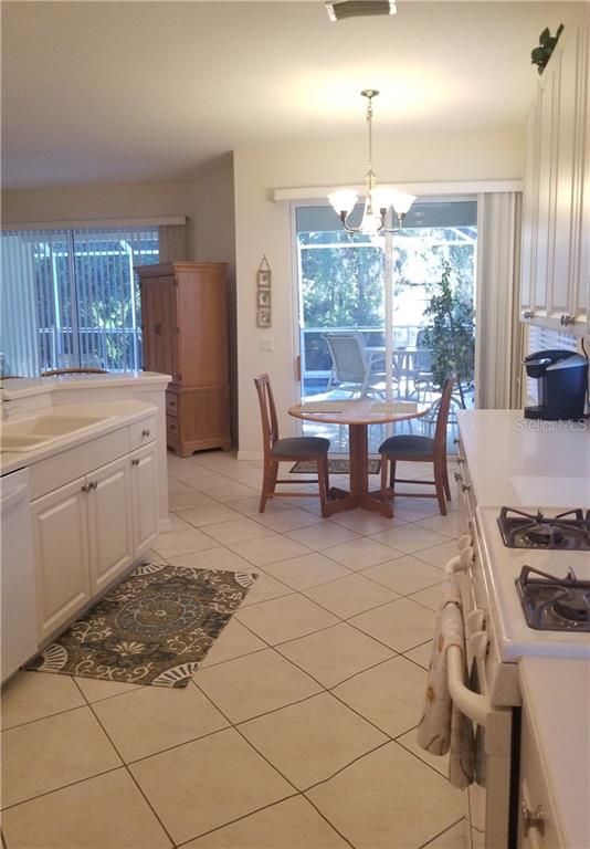 Kitchen with white cabinets, tiled floor, and rug.