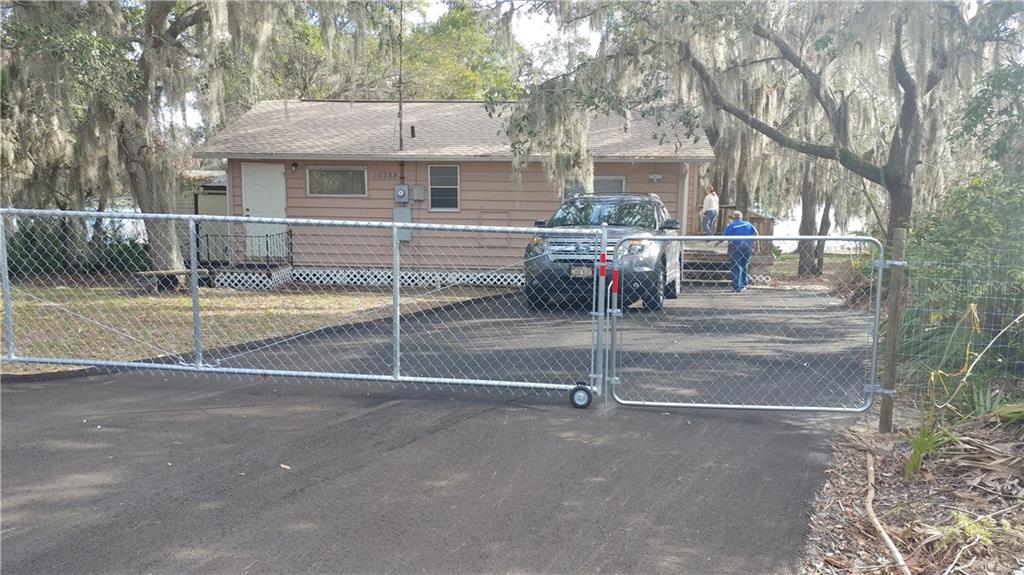 A house with a chain link gate and a car.