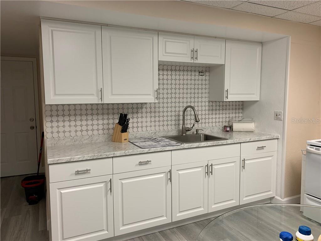 White kitchen with marble counters and tiled backsplash.