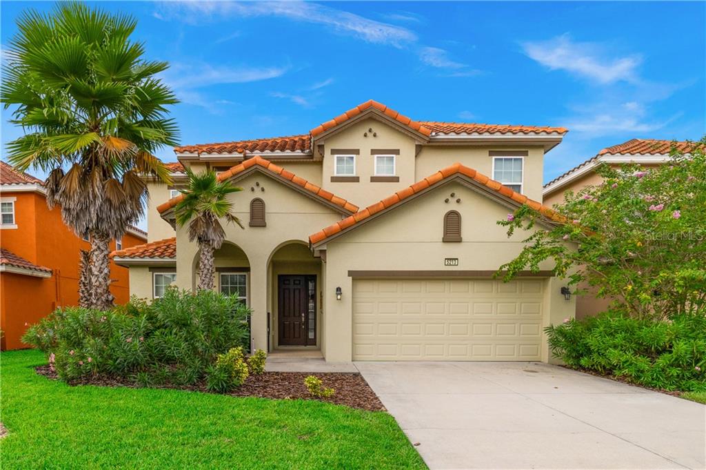 Two-story house with palm trees and a garage.