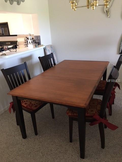 Wooden dining table with chairs and patterned cushions.