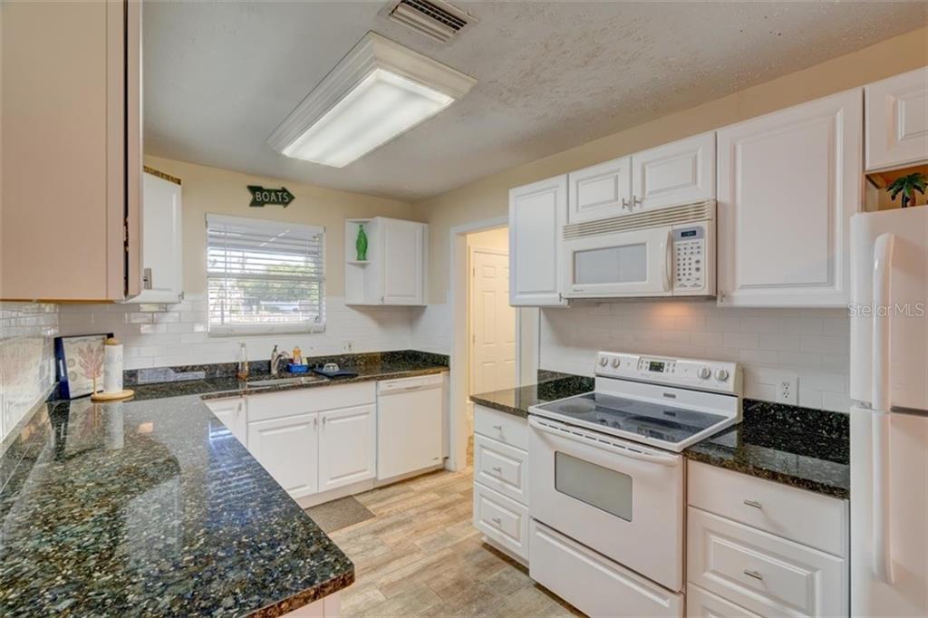 White kitchen with granite countertops and appliances.