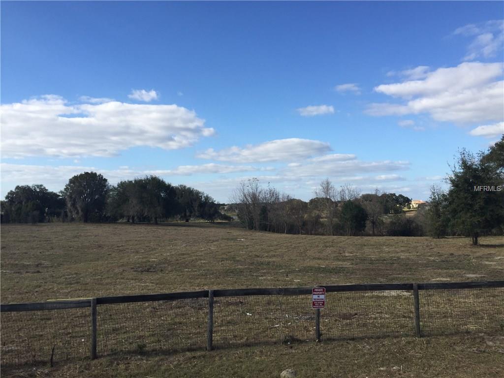 Fenced field with trees and blue sky.