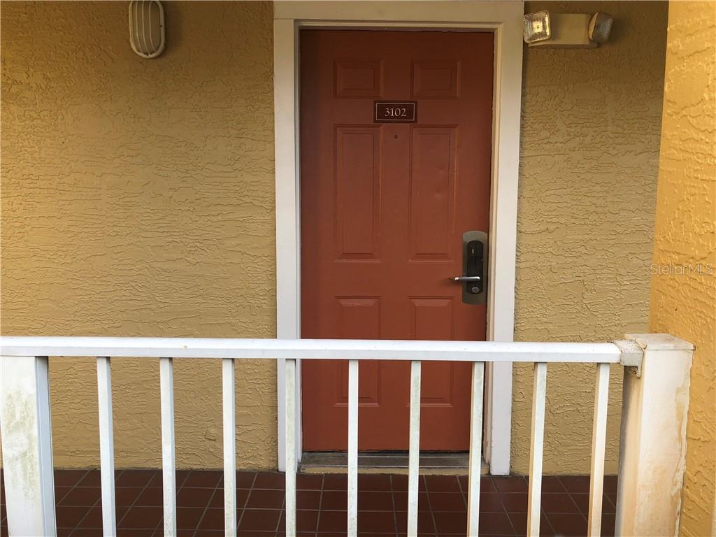 Red door with white railing and unit number 3102.