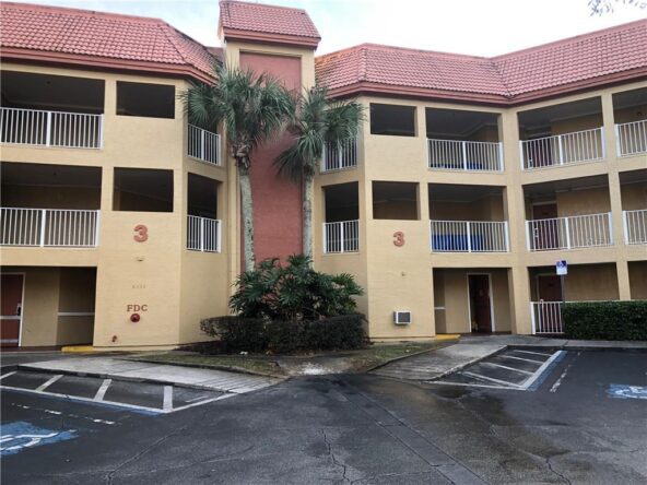 Exterior of a yellow building with palm trees.