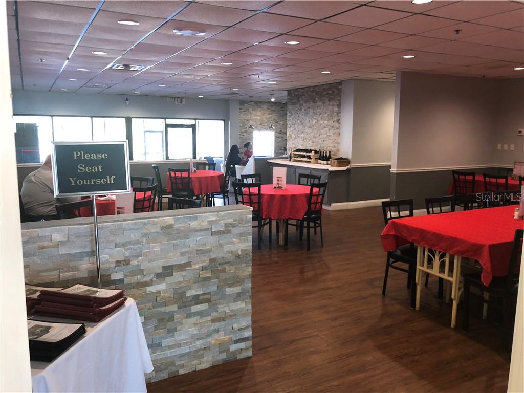 Restaurant interior with red tablecloths and chairs.