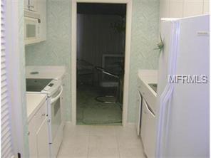 White kitchen with appliances and a doorway.