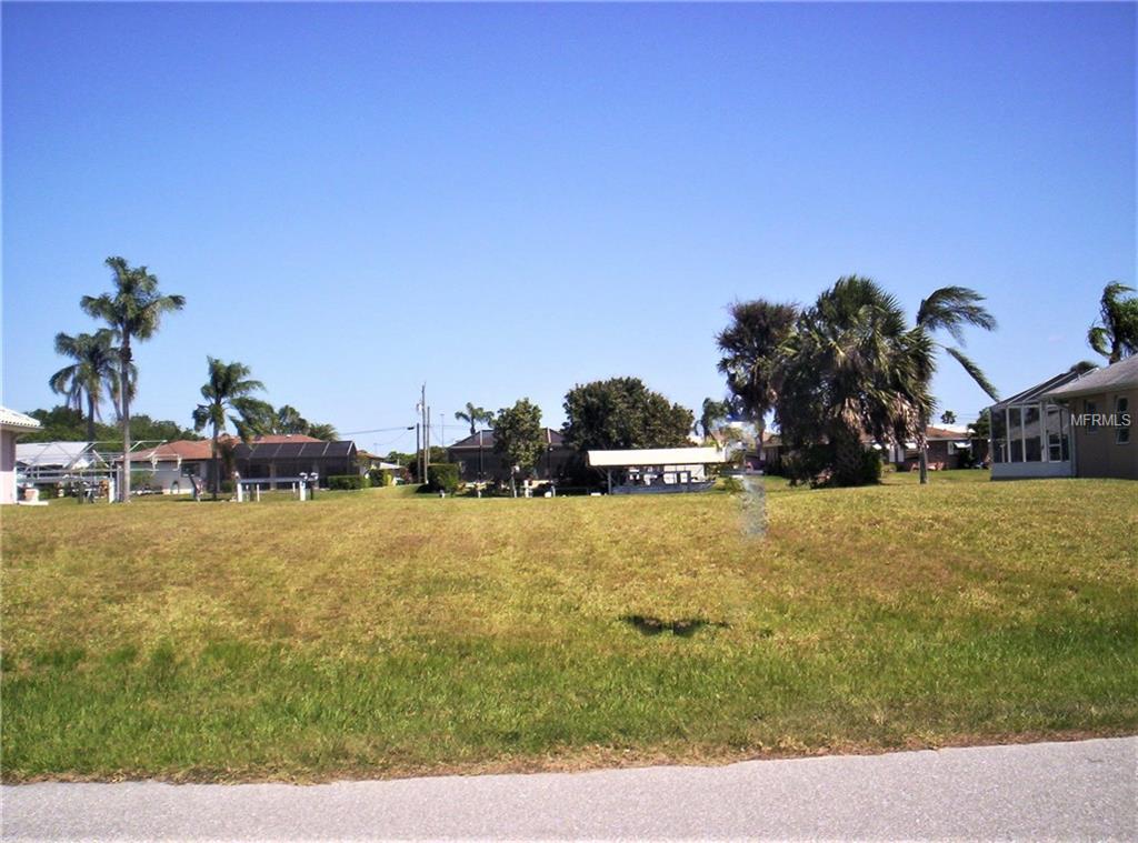 A grassy lot with homes and palm trees.