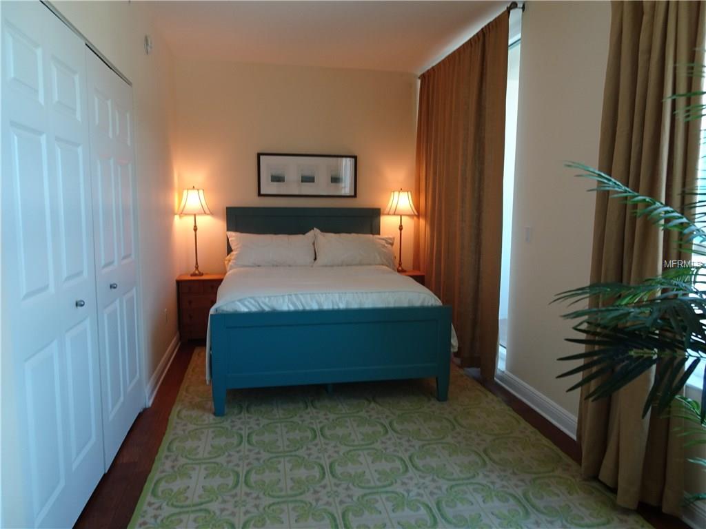 Blue bed with white bedding and green rug.