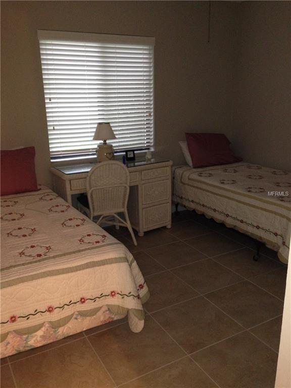 Bedroom with two beds, window blinds, and a desk.