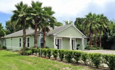 Green commercial building with palm trees.