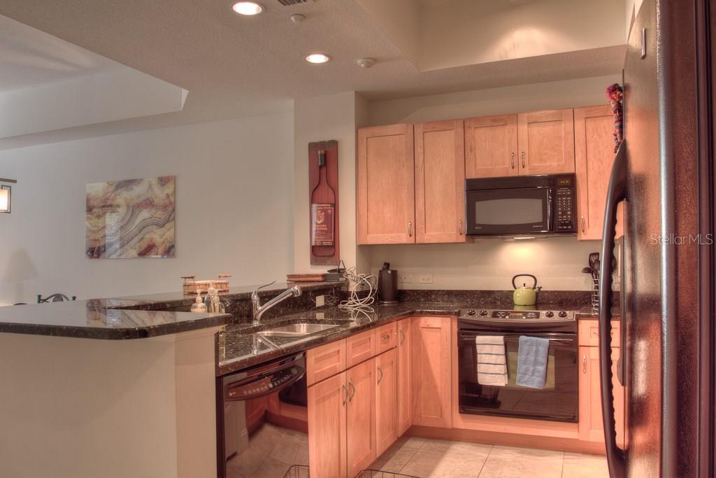 Modern kitchen with black appliances and granite counters.